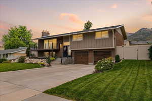 Bi-level home with brick siding, a gate, a chimney, driveway, and a balcony