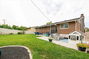 Rear view of property with a patio, a fenced backyard, brick siding, and a chimney