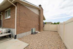 View of property exterior featuring a fenced backyard, brick siding, and a chimney