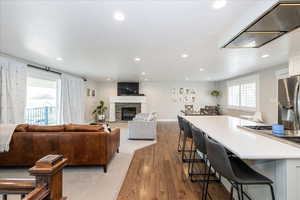 Living area with recessed lighting, dark wood-style floors, a stone fireplace, and a textured ceiling