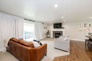 Living room featuring a stone fireplace, recessed lighting, and wood finished floors