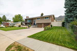 Bi-level home featuring brick siding, a balcony, an attached garage, concrete driveway, and board and batten siding
