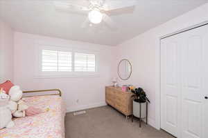 Bedroom featuring light colored carpet, a ceiling fan, and a closet