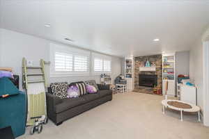 Living room featuring carpet, built in shelves, a fireplace, and a textured ceiling