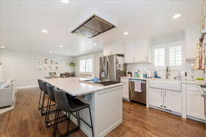 Kitchen featuring tasteful backsplash, white cabinetry, recessed lighting, a center island, and a breakfast bar