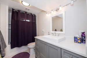 Bathroom featuring shower / bathtub combination with curtain, vanity, a textured ceiling, and light tile patterned flooring