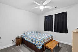 Carpeted bedroom with a ceiling fan and baseboards
