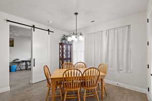 Dining room featuring a barn door, wood finish floors, and a chandelier