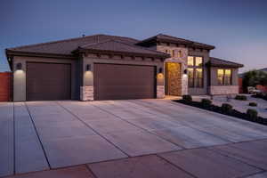 View of front facade with stone siding, an attached garage, and stucco siding