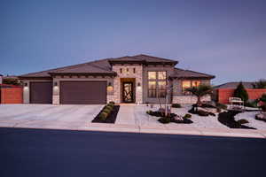 Prairie-style home featuring stone siding, driveway, an attached garage, stucco siding, and a tiled roof