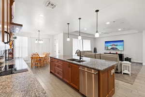 Kitchen featuring brown cabinetry, light stone countertops, dishwasher, pendant lighting, and wood tiled floors