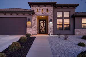 Property entrance with a tiled roof, a garage, stucco siding, and driveway