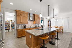 Kitchen featuring light stone counters, decorative light fixtures, a breakfast bar area, backsplash, and a barn door