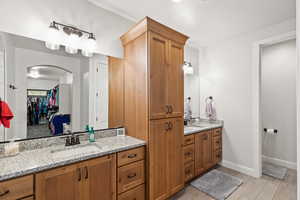 Full bathroom featuring two vanities, a spacious closet, and light wood-type flooring