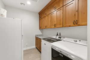 Laundry area featuring wood finish floors, cabinet space, separate washer and dryer, and recessed lighting