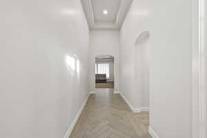 Corridor with arched walkways, a high ceiling, and recessed lighting