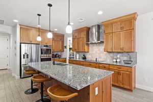 Kitchen featuring light stone countertops, tasteful backsplash, a kitchen breakfast bar, appliances with stainless steel finishes, and recessed lighting