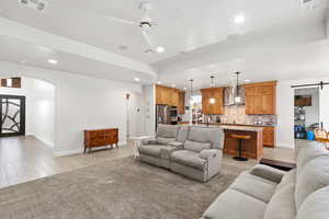 Living area with arched walkways, a barn door, ceiling fan, wood finish floors, and recessed lighting