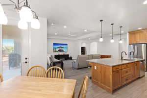 Kitchen with hanging light fixtures, a kitchen island with sink, light stone countertops, arched walkways, and open floor plan