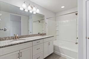 Full bathroom with double vanity, washtub / shower combination, and light tile patterned floors