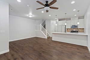Unfurnished living room with ceiling fan, dark wood-style flooring, recessed lighting, and stairway