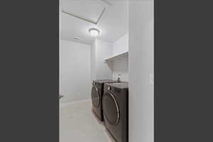 Washroom with a textured ceiling, light tile patterned floors, and separate washer and dryer