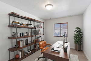 Office area featuring light carpet and a textured ceiling