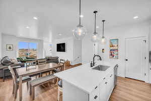 Kitchen featuring white cabinets, open floor plan, light wood-style floors, a center island with sink, and recessed lighting