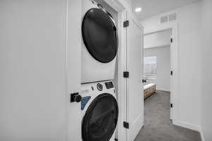 Laundry area featuring carpet flooring, stacked washer / drying machine, and recessed lighting
