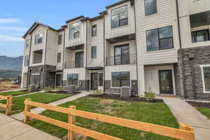 View of front of house featuring board and batten siding, stone siding, a balcony, and a residential view