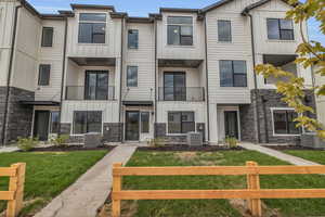 Modern inspired farmhouse with board and batten siding, a balcony, stone siding, and a residential view