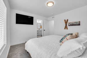 Carpeted bedroom featuring baseboards and ensuite bath