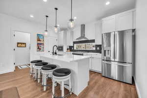 Kitchen featuring white cabinetry, appliances with stainless steel finishes, backsplash, a center island with sink, and recessed lighting