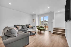 Living area featuring light wood-type flooring, recessed lighting, and stairs