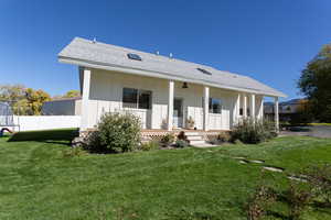 Rear view of property with covered porch, roof with shingles, and board and batten siding