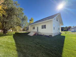 View of home's exterior with board and batten siding, a lawn, and a shingled roof