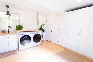 Laundry area with recessed lighting, cabinet space, washing machine and clothes dryer, and light wood-style flooring