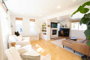 Living room featuring recessed lighting, light wood-type flooring, and a glass covered fireplace