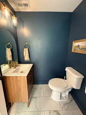 Half bath featuring light marble finish flooring and vanity