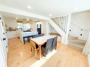 Dining room with light wood-style flooring, stairway, and recessed lighting