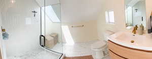 Bathroom with lofted ceiling, vanity, a shower stall, and a skylight