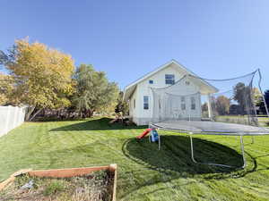View of side of home with a trampoline, a playground, a fenced backyard, and board and batten siding
