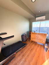 Workout room with light wood-style flooring, recessed lighting, and an AC wall unit