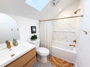 Bathroom with vaulted ceiling, shower / bath combo with shower curtain, a skylight, vanity, and recessed lighting