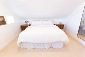Bedroom featuring light colored carpet and lofted ceiling