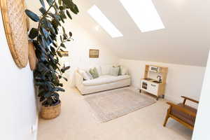 Living area featuring carpet flooring, a skylight, lofted ceiling, and recessed lighting