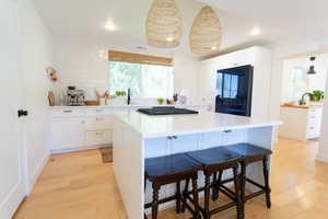 Kitchen featuring white cabinetry, a breakfast bar, a kitchen island, recessed lighting, and light wood-style floors