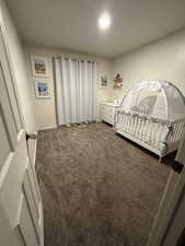 Carpeted bedroom featuring baseboards and a crib
