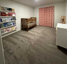 Bedroom with dark colored carpet and baseboards