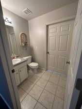 Half bathroom with a textured ceiling, vanity, and light tile patterned flooring